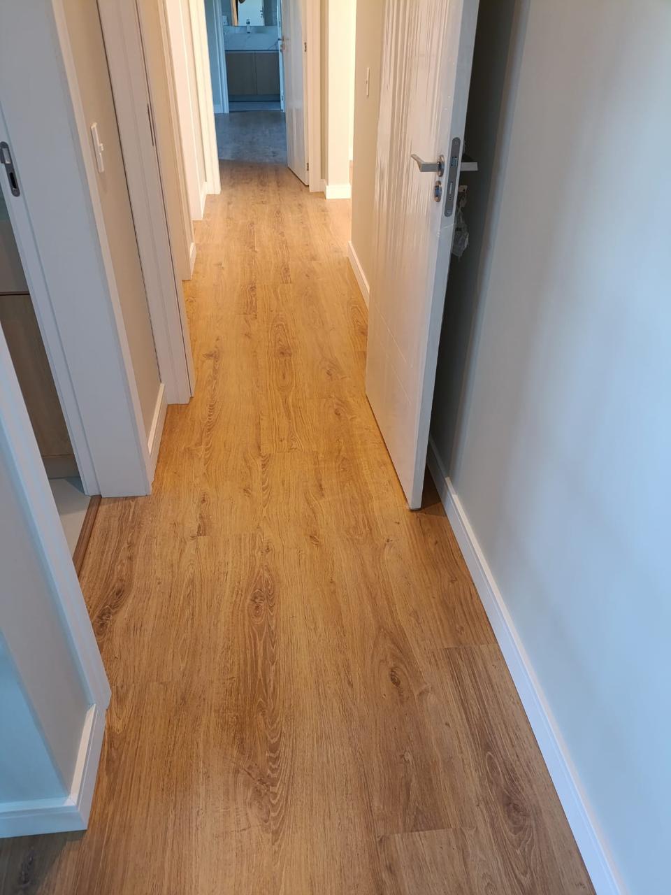 Piso laminado em corredor com portas brancas